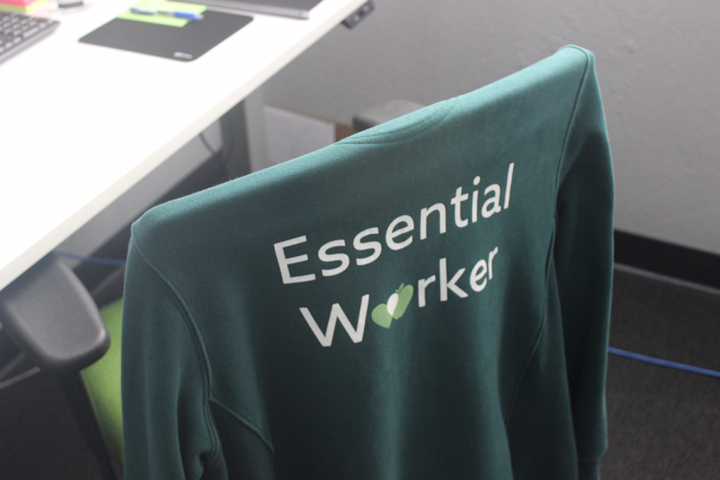 A green jacket rests on the back of a rest chair. The back of the jacket reads "Essential Worker."
